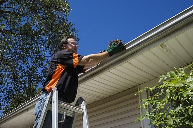 workman on a ladder repairing a broken gutter in Christmas